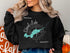Black sweatshirt with "Beautiful Shoal Lake Ontario" text and compass graphic.
