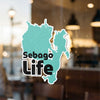 Turquoise Sebago Life sticker on glass with blurred background.