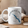White mug with "SAYLORVILLE LAKE" text, blue Iowa map, and compass rose graphic.