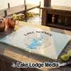 A rectangular glass cutting board with a blue Lake Norman map and compass design sits on a wooden dock.
