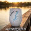 A white travel tumbler featuring a blue map of Jordan Lake, North Carolina, resting on a wooden dock at sunset.