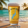 Glass of beer with "Lake Bomoseen" text and Vermont map on a beach.