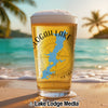 Glass of beer with "Slogan Lake" and Oklahoma map design on a beach.