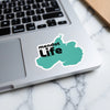 Turquoise "Mendot Life" sticker on a laptop keyboard with marble background.