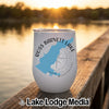 A white insulated wine tumbler with a blue map of Ross Barnett Lake sits on a wooden dock at sunset.