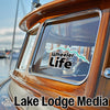 Wheeler Life logo and Lake Lodge Media text on a boat's wooden cabin.