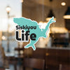 Turquoise outline sticker with "Siskiyou Life" text on a window with blurred background.