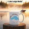 White mug with Lake Superior map, compass, and text on a waterfront background.