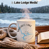 White mug with Mitchell Lake Alabama map and compass, steam rising, by a window.