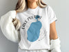 White t-shirt with blue Lake Pulaski, Minnesota, compass design.