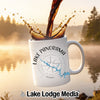 White mug with "Lake Panorama" text and compass design, with coffee pouring.