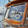 Bluestone Life logo sticker on a wooden boat window beside Lake Lodge Media text.