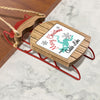 Ornament with "Merry Christmas FROM Caddo Lake" text on a wooden sled.