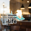Woods Canyon Life sticker with turquoise outline on glass