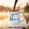 White mug with Grenada Lake map and compass logo, coffee pouring.