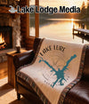 Cream blanket with blue lake map and compass on a brown leather couch.