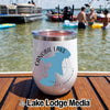 A white insulated wine tumbler with a Canobie Lake New Hampshire graphic sits on a wooden boat deck with people swimming in the lake behind it.