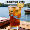 Iced tea in a glass with a Gray Lake design and a lemon slice, by a lake.