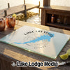 A glass cutting board with a blue Lake Las Vegas map graphic rests on a wooden table outdoors.