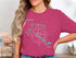 Pink t-shirt with "Beautiful Lake Panorama" graphic and compass rose.