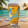 Glass of beer with blue Oklahoma lake map and compass design on beach.