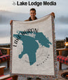 Man holding a woven throw blanket featuring a teal map of Lake Huron, Michigan.