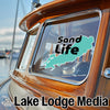 Turquoise outline with black text "Sand Life" logo on boat window, "Lake Lodge Media" text below.