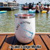 A white stemless wine tumbler with Lake Sonoma California printed on the side, resting on a wooden boat deck with people swimming in the background.
