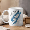 White mug with Lake Placid map and compass design, steaming hot.