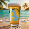 Glass of beer on a beach with a blue Iowa map overlay and "EST OKOBOJI LAN" text.