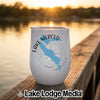 A white insulated tumbler featuring a blue map of Lake Merced, California, sits on a wooden dock at sunset.