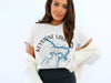 Woman in white t-shirt with "Keystone Lake Oklahoma" map and compass design.