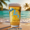 Pint glass of beer with "Evergreen Lake" and Illinois map on a beach.