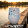 A white insulated tumbler featuring a blue map graphic of Falls Lake, North Carolina, resting on a wooden dock.