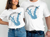 White t-shirts featuring a blue map of Calaveras Lake, Texas, with a compass rose.