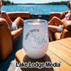 A white insulated wine tumbler with Lake Travis compass design sits on a wooden boat table.