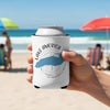 White koozie with blue Lake Michigan map, compass, and text on a beach.