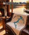 Blanket with Lake Coeur d'Alene map and compass design on leather sofa.
