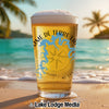 Glass of beer with "Mme de Terre Lac" and compass design on a beach.