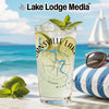 Glass of iced lime drink with mint, sunglasses on striped pillow, beach background.