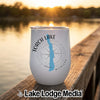 A white tumbler featuring a blue Torch Lake outline and compass design rests on a wooden dock.
