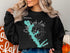 Black sweatshirt featuring a teal Cedar Creek Lake map and compass design.