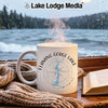 White mug with Flaming Gorge Lake compass design, steam rising, with lake view.