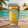 Glass of beer with Lake Lotawana outline and compass on a beach background.