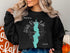 Black sweatshirt with "Beautiful White Rock Lake Texas" text and a teal lake graphic.