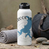 White water bottle with blue map and compass design, next to a rolled towel and duffel bag.