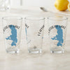 Three clear pint glasses, each featuring a blue Flathead Lake map and compass design.