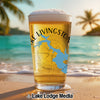 Glass of beer with "Lake Livingston" and Texas map design on beach background.