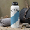 White water bottle with "Dict Lake" and compass map graphic, next to rolled towel and duffel bag.