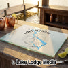 A tempered glass cutting board featuring a Lake Sonoma, California map and compass design sits on a wooden dock.